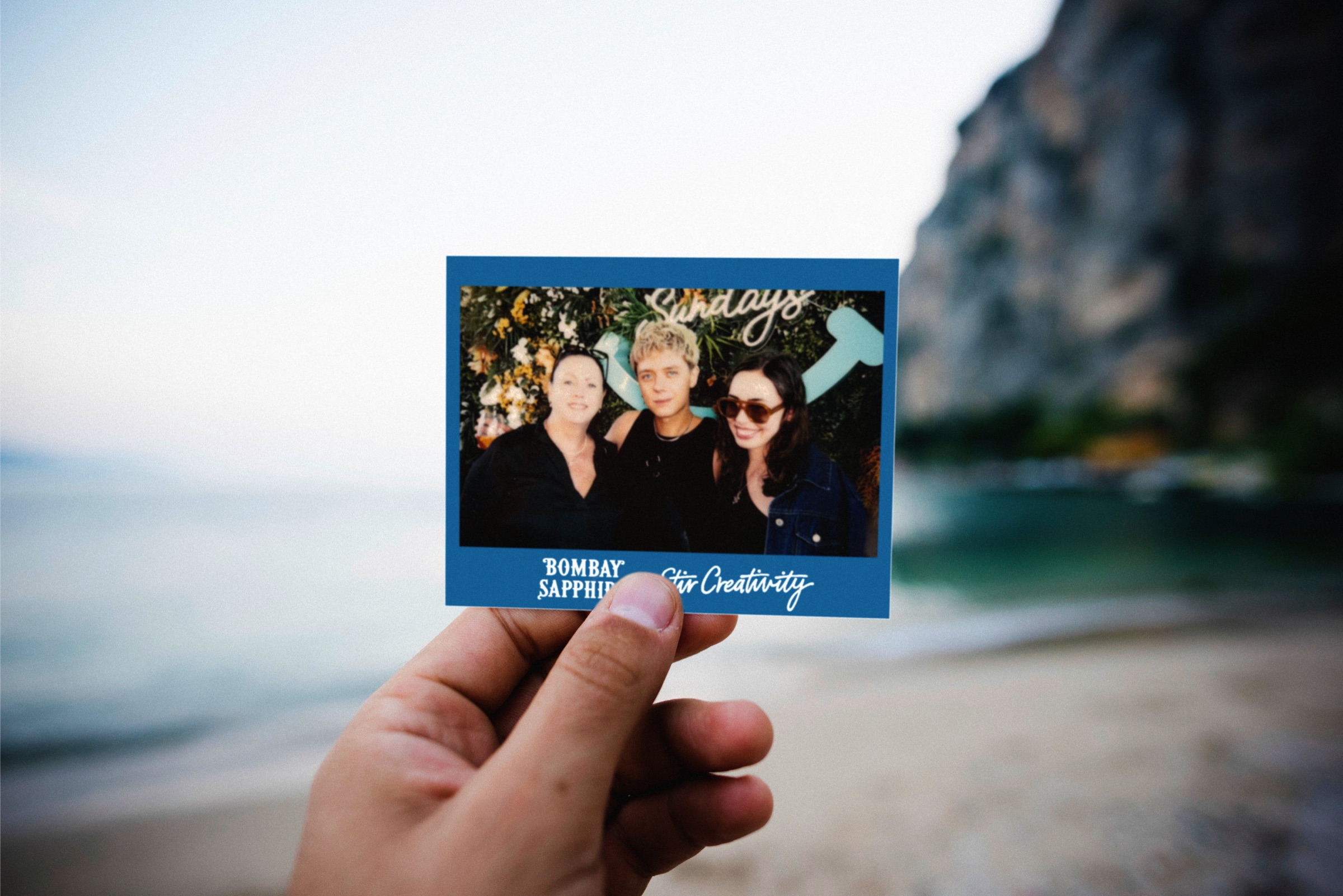 Holding an instant camera by the beach